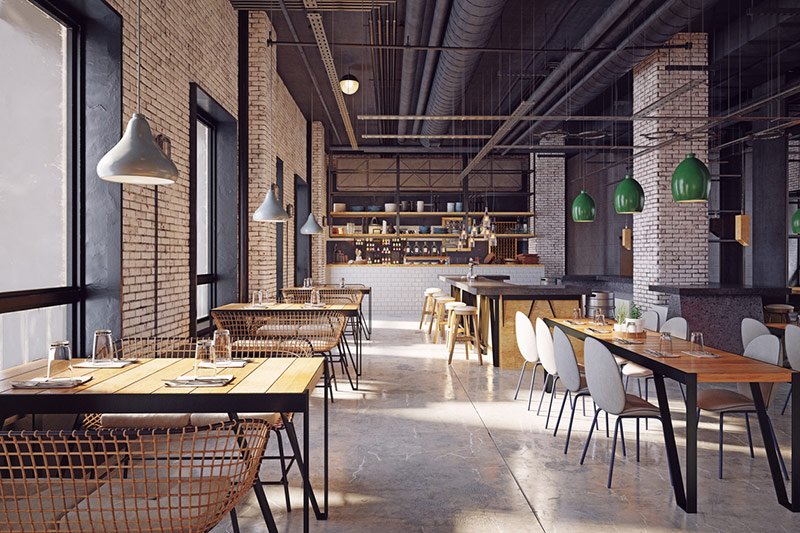 Empty restaurant dining room with industrial style decor and lamps hanging above each table and from the high ceiling